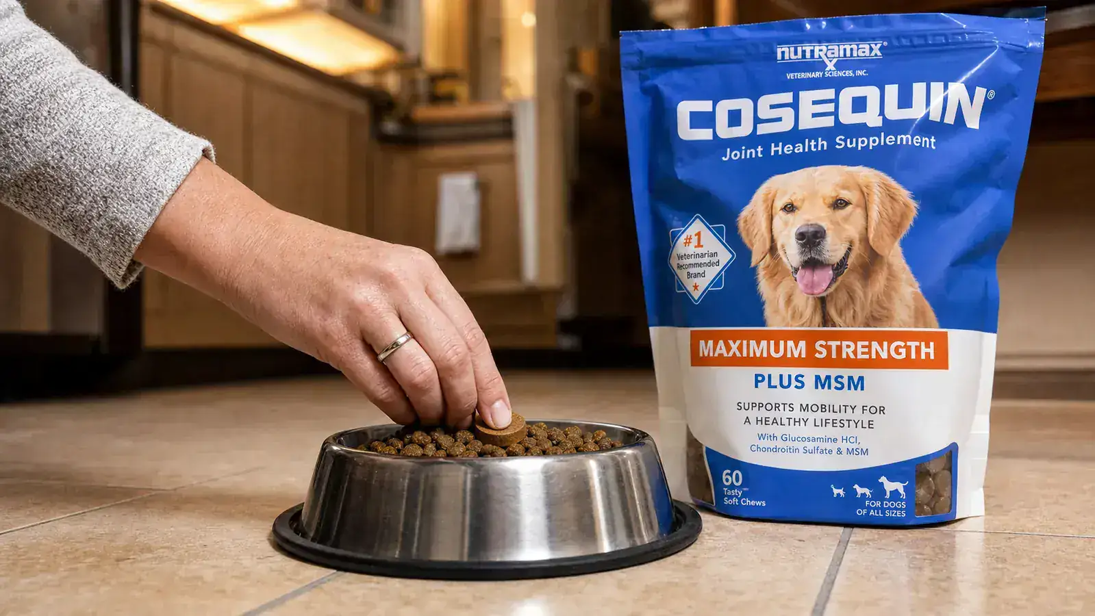 Person placing a Cosequin joint supplement chew on top of kibble in a stainless steel dog bowl